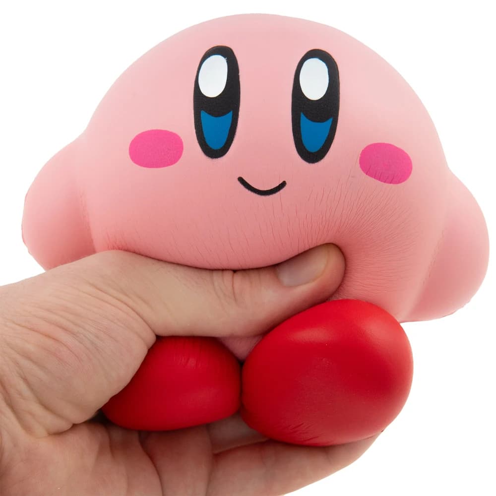 Händlerabbildung des rosa Kirby Mega Squish Me Stressballs, der von einer Hand zusammengedrückt wird